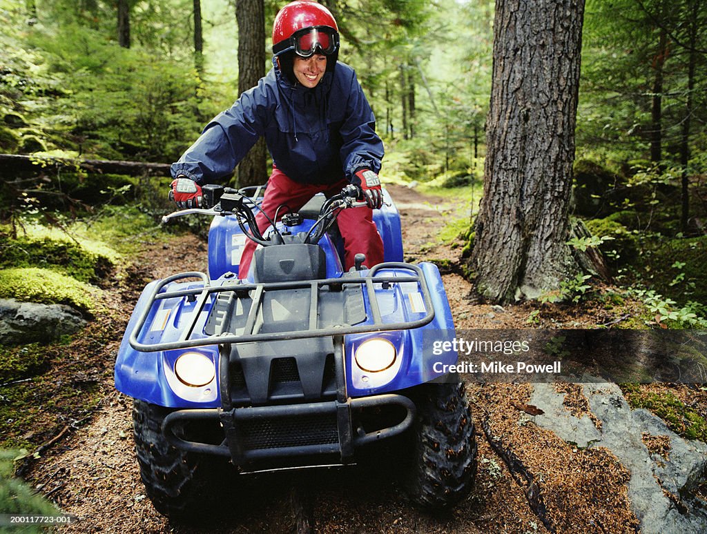 Woman driving ATV through forest