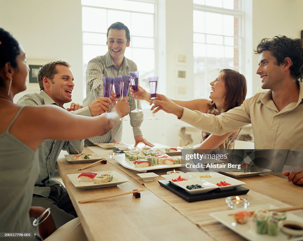 Group of people raising toast at dinner table