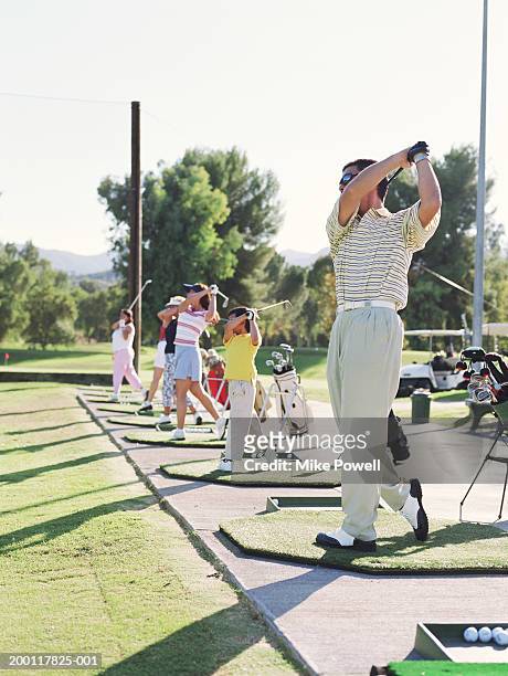 line of golfers mid swing on driving range - driving range stock pictures, royalty-free photos & images
