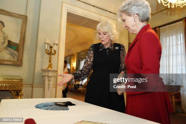 Queen Camilla and Birgitte, Duchess of Gloucester observe a fan ahead of a ceremony at Clarence House, where she will be installed as an Honorary...