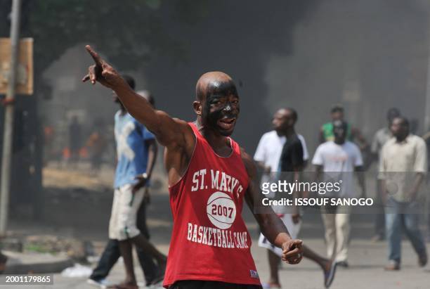 Supporters of Ivory Coast's presidential candidate Alassane Ouattara shout as they protest and burn tyres in the streets of Abidjan on December 4,...