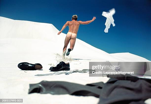 naked businessman running on beach, discarding clothes, rear view - raya del bronceado fotografías e imágenes de stock