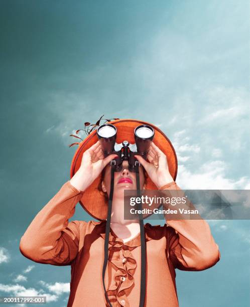 young woman looking through binoculars, low angle view - canocchiale foto e immagini stock