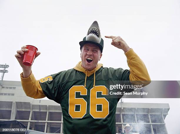 man pointing at cap with shark  design at stadium parking lot - sports fan stock-fotos und bilder