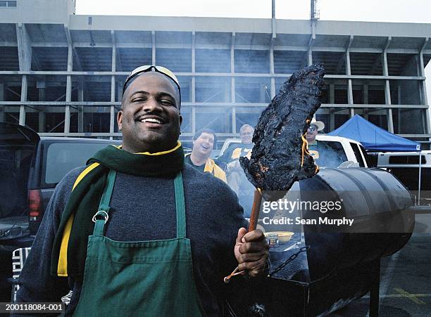 men having tailgate party, man holding burned out steak - cut of meat stock pictures, royalty-free photos & images