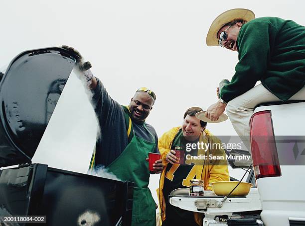 men barbequeing at tailgate party  in stadium parking lot - open collar fotografías e imágenes de stock