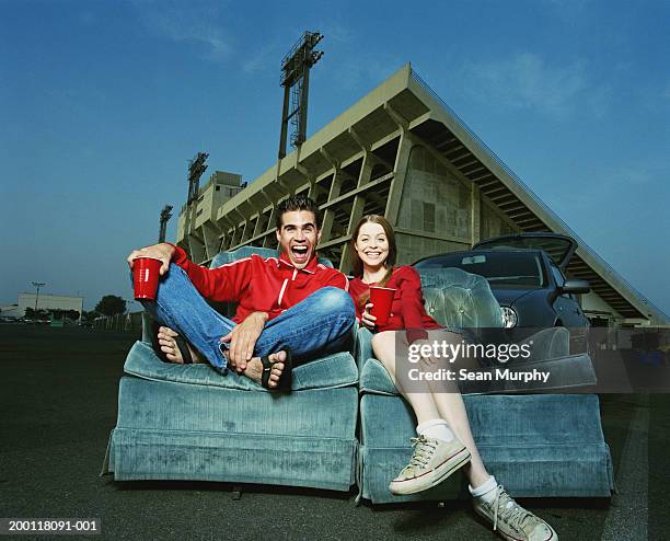 young couple sitting on lounge chairs in stadium parking lot - fehl am platz stock-fotos und bilder