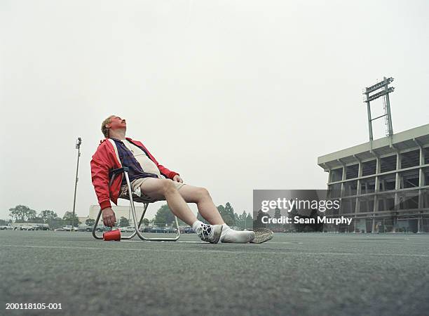 man sleeping in folding chair in stadium parking lot - betrunken stock-fotos und bilder