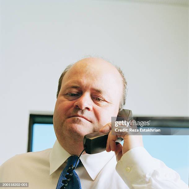 mature businessman holding telephone receiver - stoneplus1 stock pictures, royalty-free photos & images