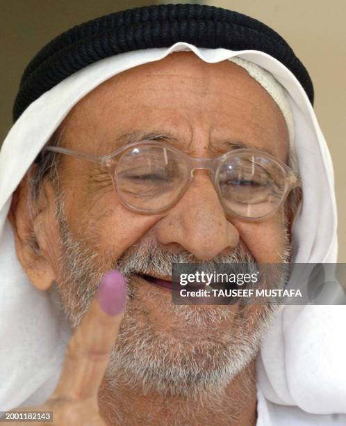 An elderly Iraqi shows his indelible ink-stained finger after voting in a referendum on Iraq's draft constitution 15 October 2005, at a polling...
