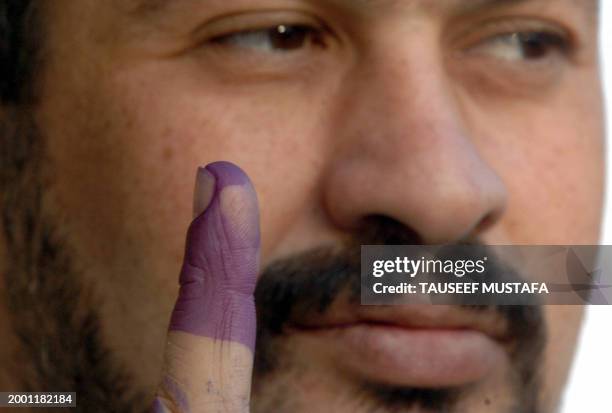 An Iraqi man shows his finger after dipping it in ink and casting his vote inside a polling station during the landmark referendum on a new...