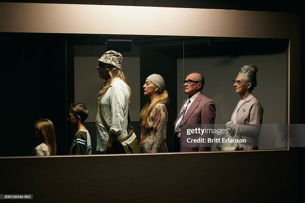 People standing in line behind glass partition