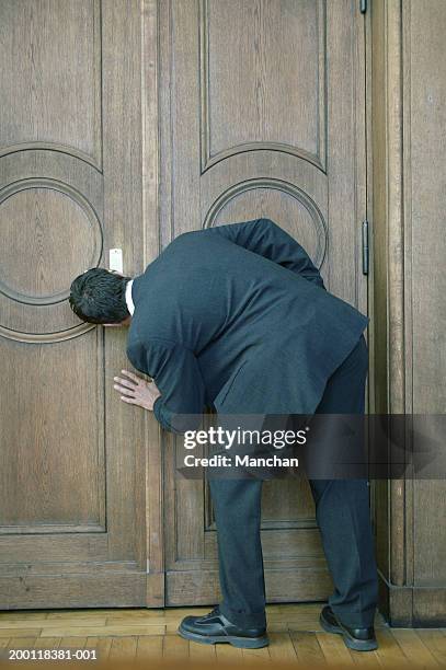 man looking through keyhole of door, rear view - durchblick schlüsselloch stock-fotos und bilder