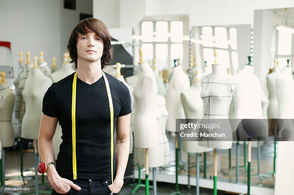 Man with tape measure round neck in fashion studio, portrait