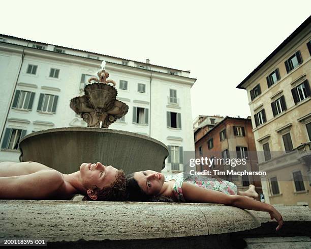 teenage couple (16-18) lying head to head on edge of fountain - hot boy body stock pictures, royalty-free photos & images