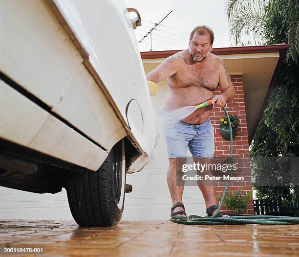 man washing car in driveway, ground view - bierbauch stock-fotos und bilder