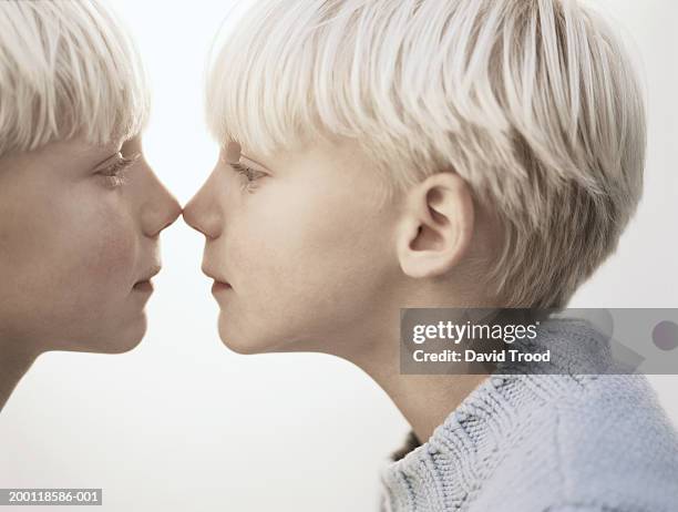 twin boys (6-8) standing face to face, noses touching, close-up - cloning stock-fotos und bilder
