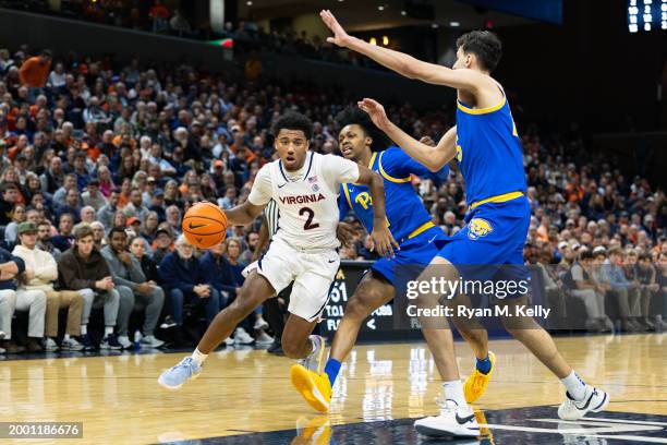 Reece Beekman of the Virginia Cavaliers drives against Carlton Carrington and Guillermo Diaz Graham of the Pittsburgh Panthers in the second half at...