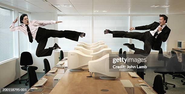 two men kicking in mid-air across row of computers (digital composite) - mêlée stock-fotos und bilder