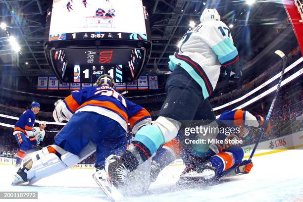 Kyle Palmieri of the New York Islanders is hit by Jaden Schwartz of the Seattle Kraken as Ilya Sorokin tends net during the third period at UBS Arena...