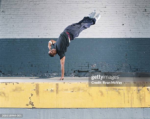 young man breakdancing on loading dock, balancing on one hand - hip hop dance fotografías e imágenes de stock