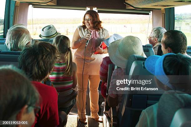 tour guide holding microphone at front of coach full of tourists - guide bildbanksfoton och bilder