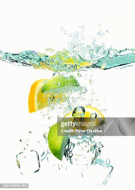 ice cubes and wedges of  lemon and lime floating in liquid - citrus splash stock pictures, royalty-free photos & images