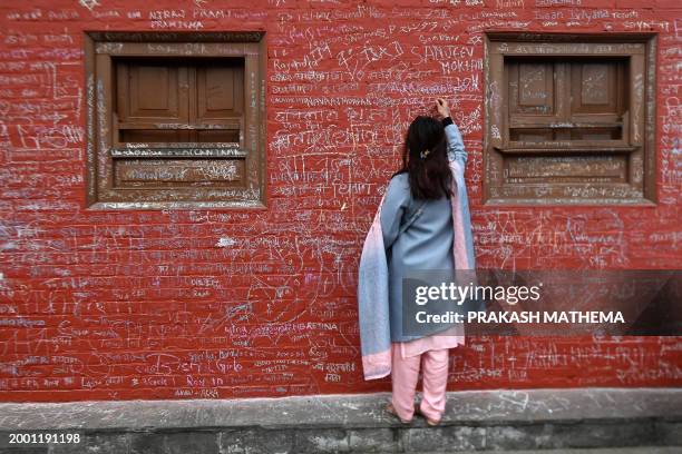 Devotee writes a message with chalk on a wall at the Saraswati temple on the occasion of the Hindu festival of 'Basanta Panchami', in Kathmandu on...