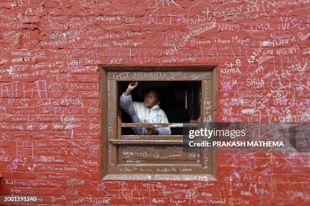 Child writes a message with chalk on a wall at the Saraswati temple on the occasion of the Hindu festival of 'Basanta Panchami', in Kathmandu on...