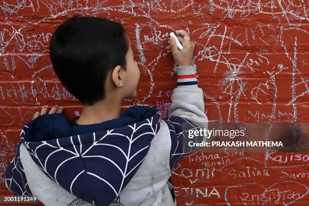 Child writes a message with chalk on a wall at the Saraswati temple on the occasion of the Hindu festival of 'Basanta Panchami', in Kathmandu on...