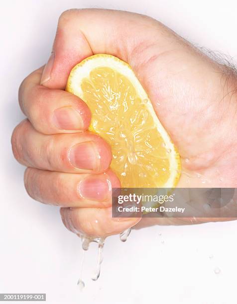 man squeezing cut lemon in fist, close-up - quetschen stock-fotos und bilder