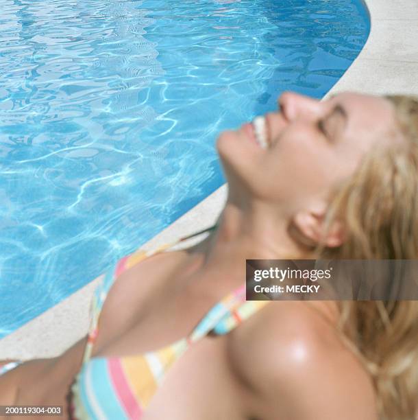 young woman relaxing by pool (focus on background) - stoneplus1 stock pictures, royalty-free photos & images