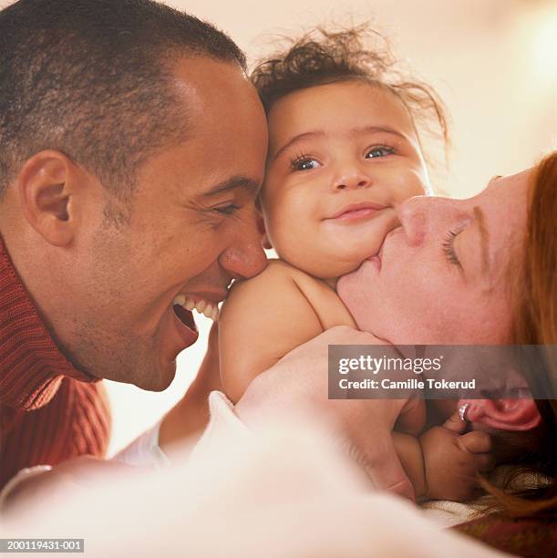 parents kissing baby daughter (3-6 months), close up - baby father hug side stock pictures, royalty-free photos & images