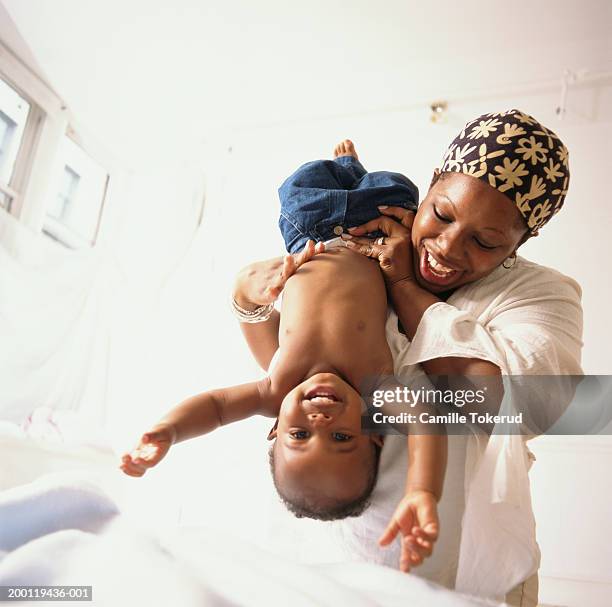 mother holding baby boy (6-9months) upside down, smiling - holding upside down stock pictures, royalty-free photos & images