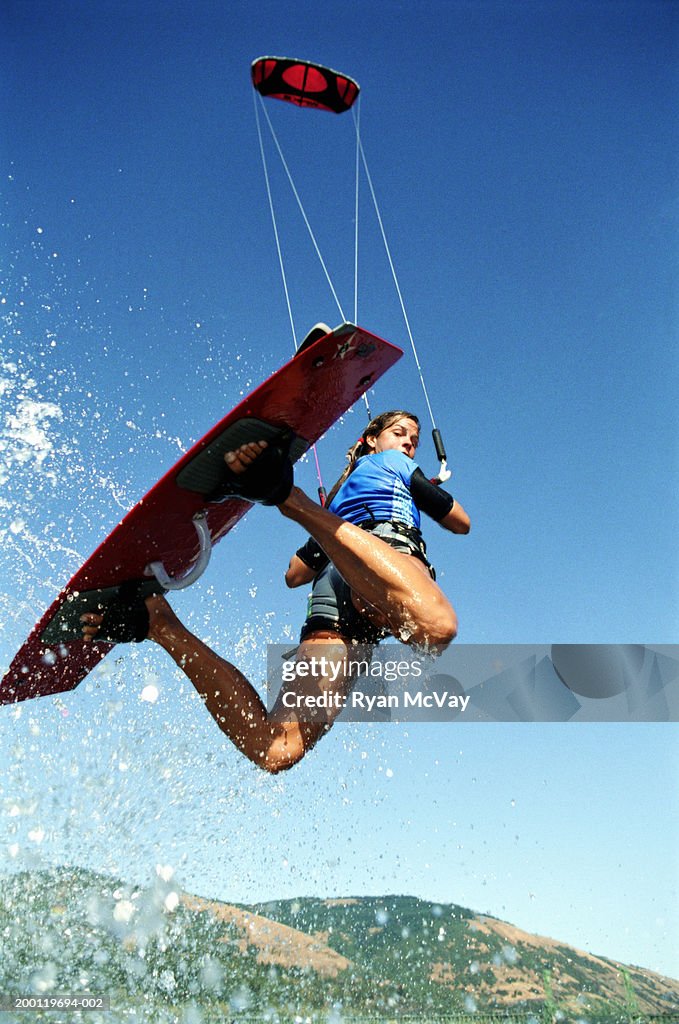 Female kiteboarder in mid-air, looking over shoulder, low angle view