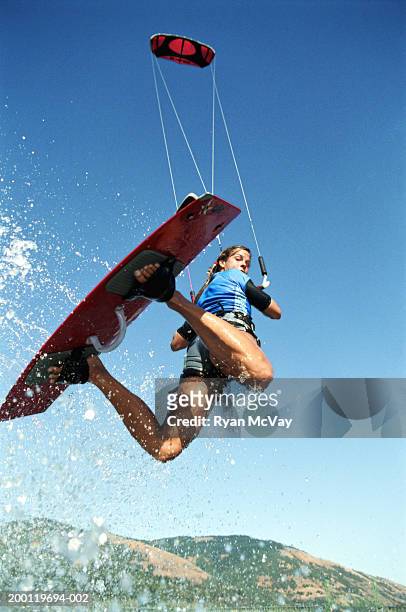 female kiteboarder in mid-air, looking over shoulder, low angle view - kite stock pictures, royalty-free photos & images