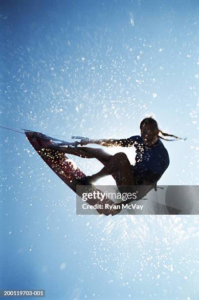 female kiteboarder in mid-air, silhouette, low angle view - kitesurf photos et images de collection