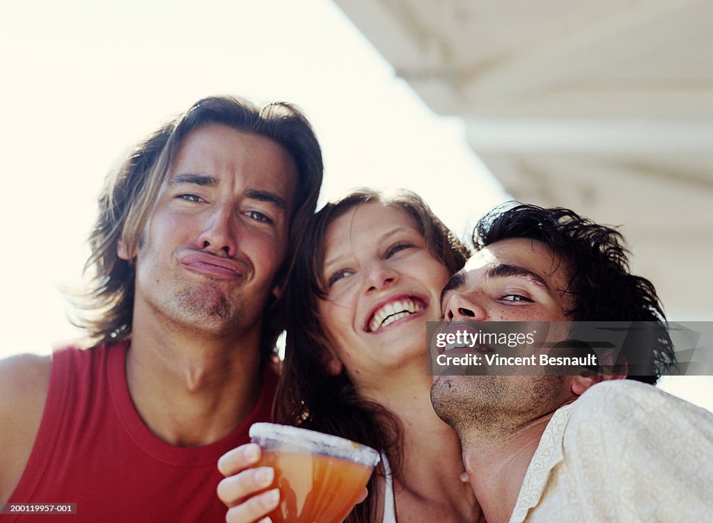 Three friends outdoors, man pulling face, portrait