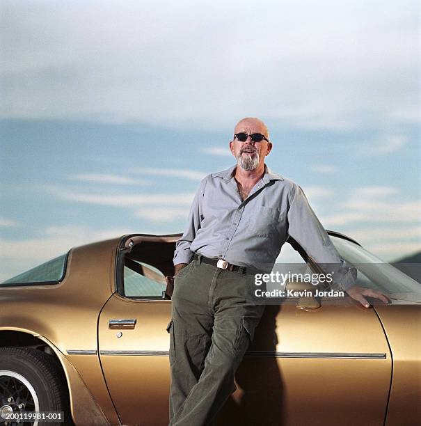 mature man leaning against sports car, portrait - sportwagen stockfoto's en -beelden