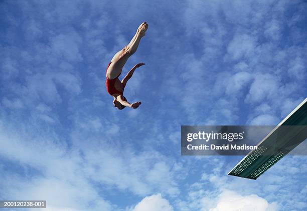 woman diving off diving board, low angle view (digital composite) - dive stockfoto's en -beelden