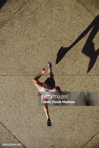 man jogging on sidewalk (overhead view) - running shadow stock-fotos und bilder