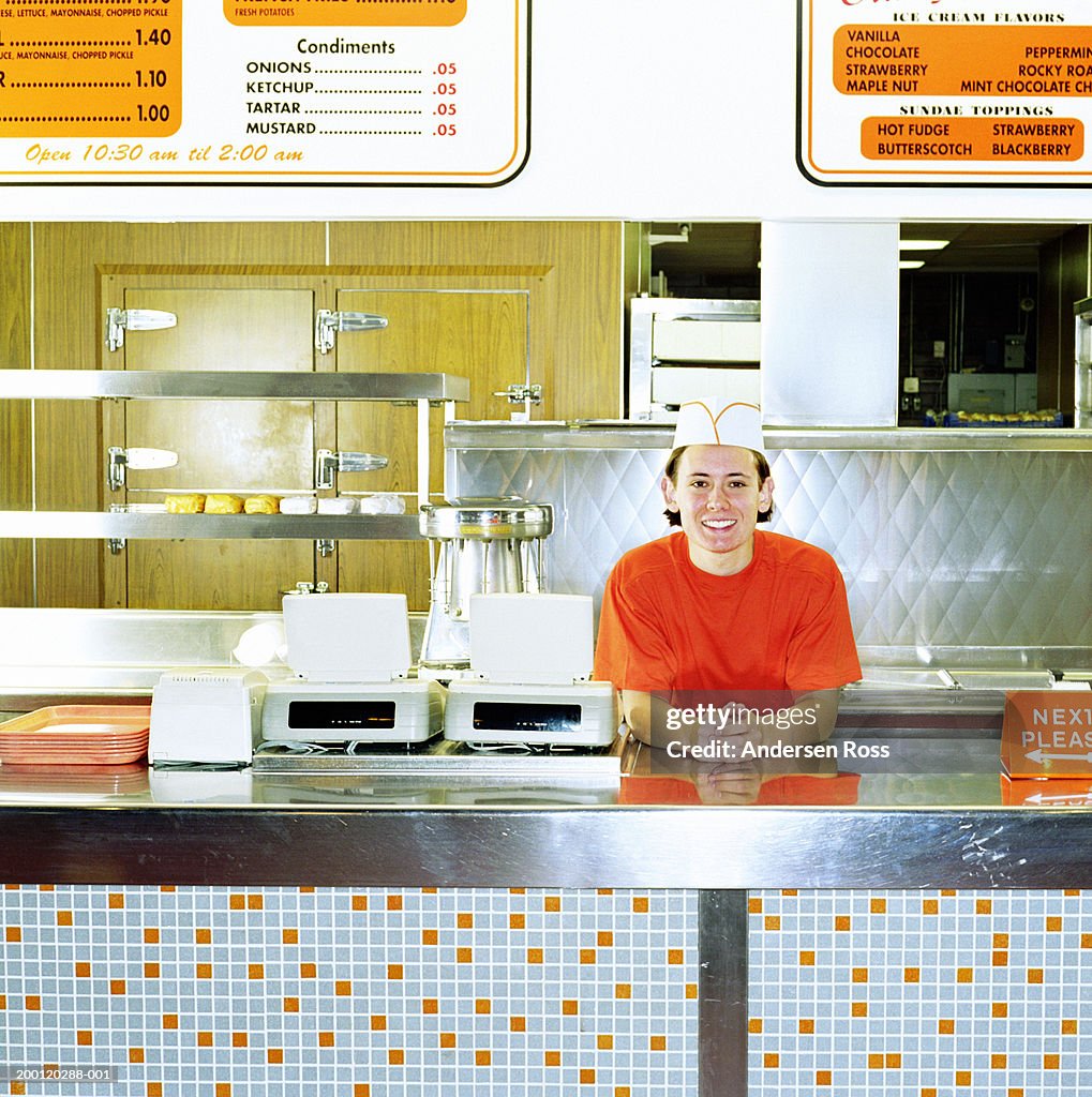 Teenage boy (17-19) working behind counter of fast-food restaurant