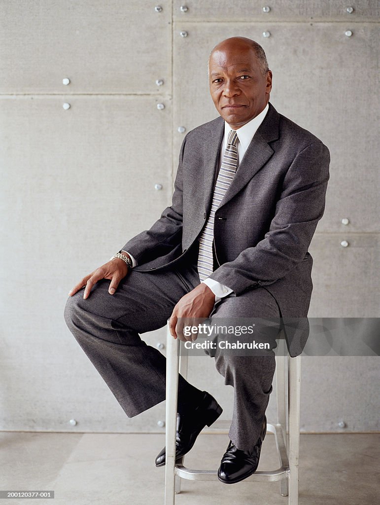 Mature business man sitting on stool, portrait