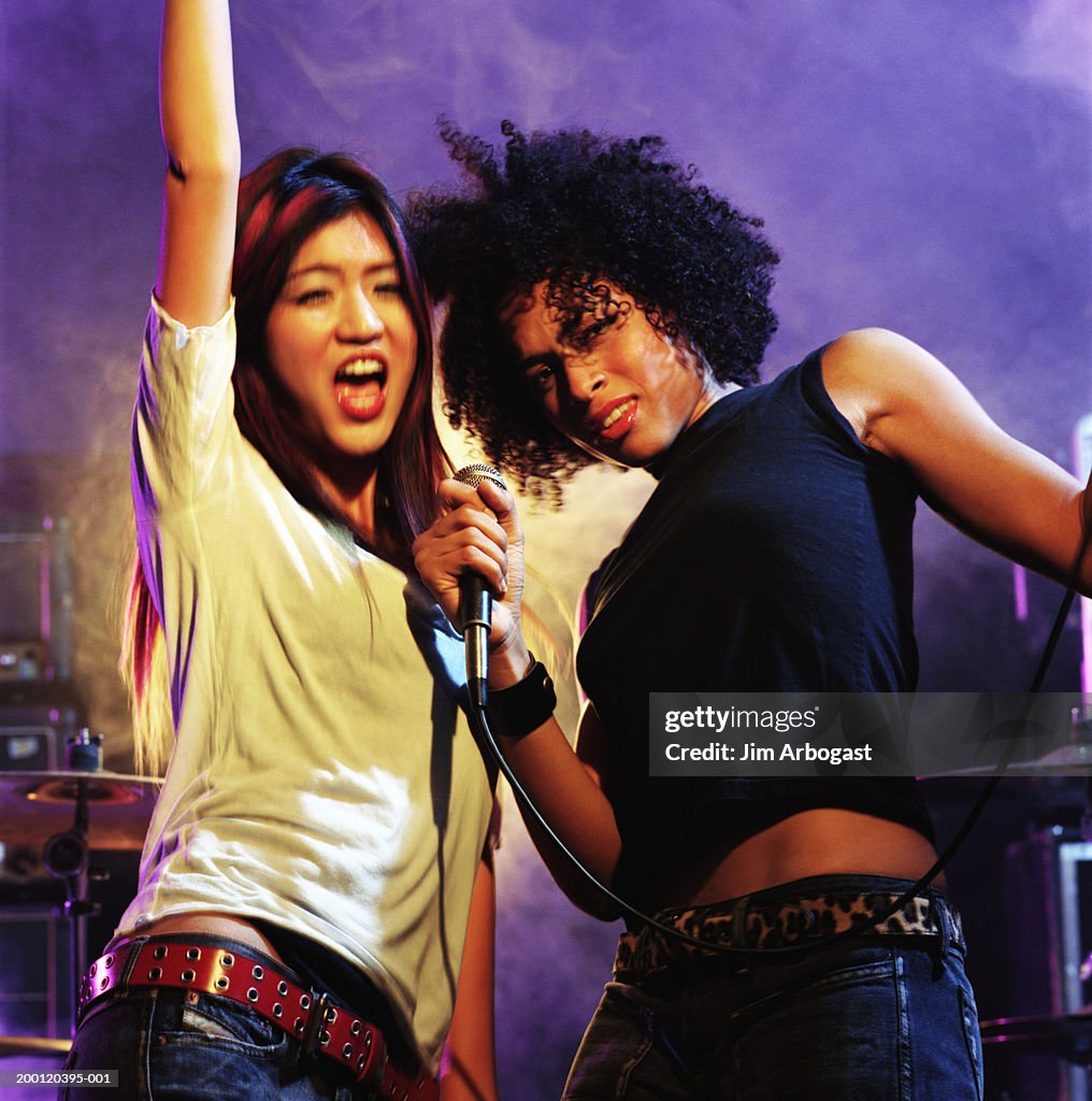 Two young women singing into microphone, close-up (blurred motion)