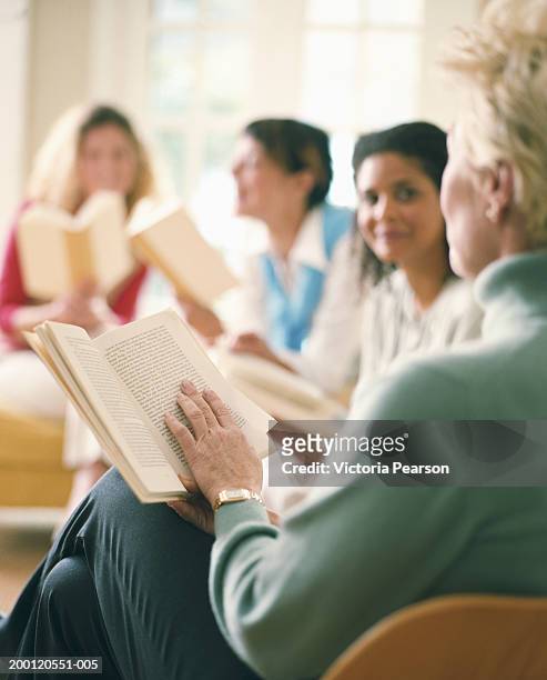 women reading in book club, rear view, (focus on book) - book club meeting stockfoto's en -beelden