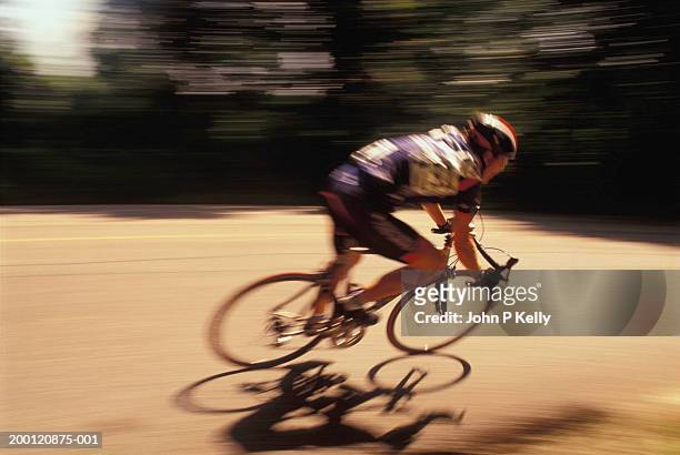 man riding racing bicycle, side view (blurred motion) - track cycling stock-fotos und bilder