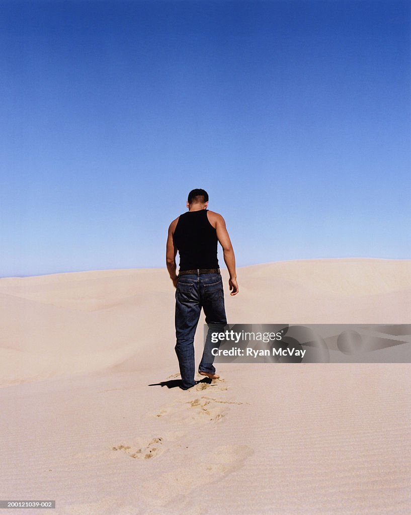 Jovem homem a caminhar até Duna de Areia, vista traseira