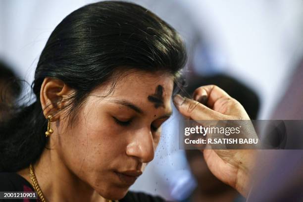 Priest marks the cross symbol with ash on the forehead of a Christian devotee during an Ash Wednesday mass service at St. Thomas Cathedral Basilica...