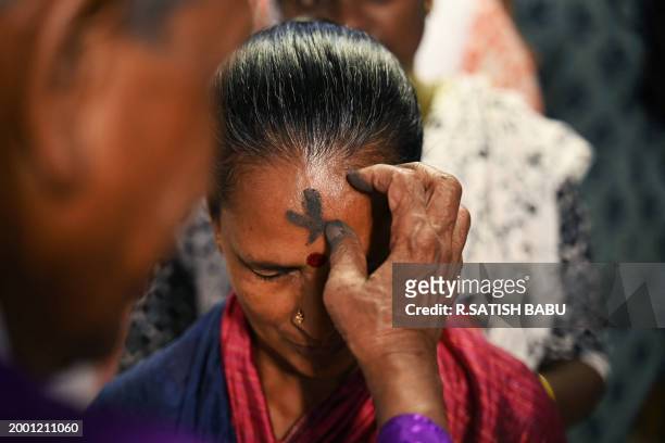 Priest marks the cross symbol with ash on the forehead of a Christian devotee during an Ash Wednesday mass service at St. Thomas Cathedral Basilica...