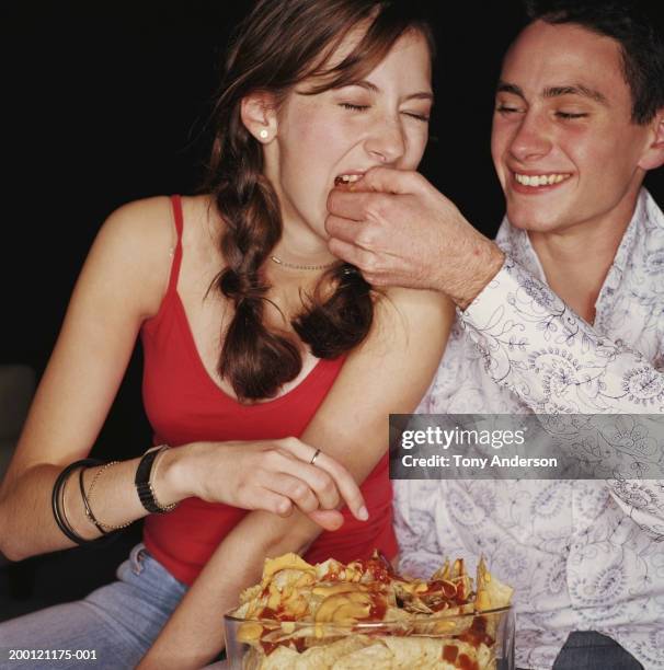 teenage couple (15-18) eating nachos - nachos stockfoto's en -beelden